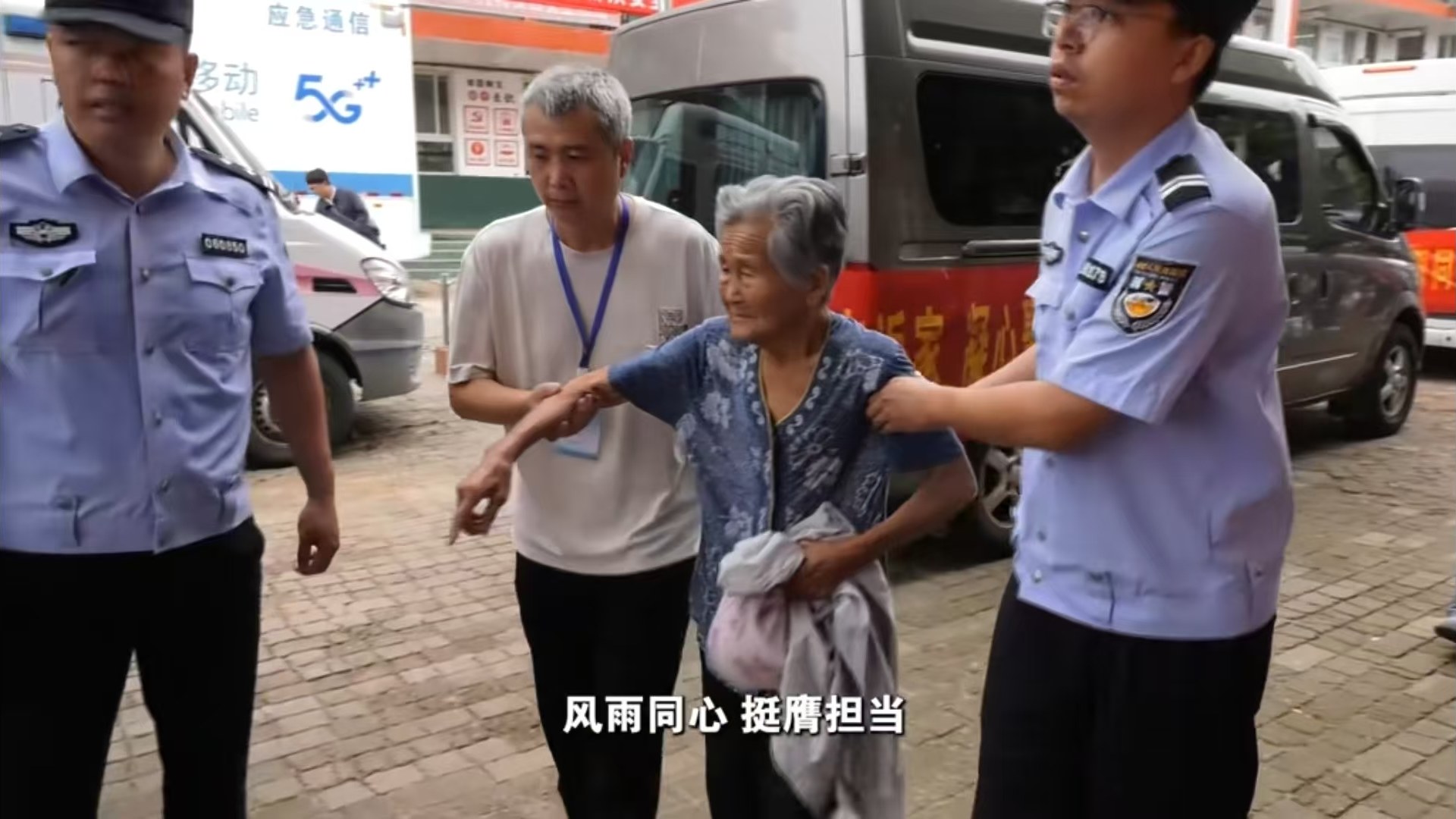 民警与工作人员搀扶老人在安置点外转移（央视新闻画面）